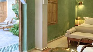 Una habitación con cama, una silla, una mesita y una ventana.