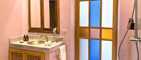 A bathroom with a sink, mirror, towel rack, and a shower with a glass door.