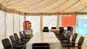 A tented meeting room with a long table and chairs arranged around it. - Camp OM Riverside Retreat (Pokhri)