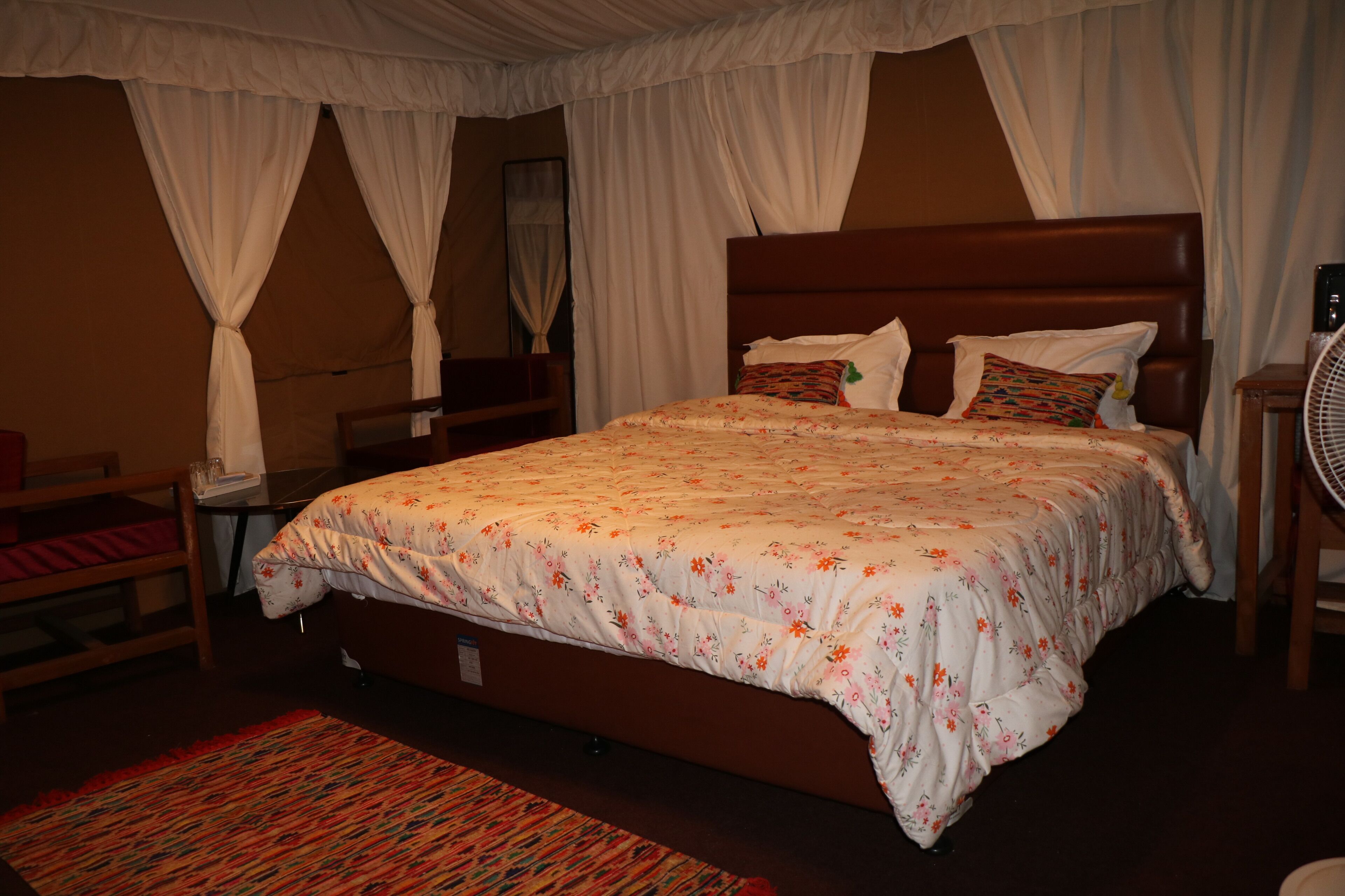 Une chambre à coucher avec un grand lit, une tête de lit en bois, une table de chevet et une lampe de chevet.
