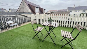 A rooftop terrace with artificial grass, two wooden folding chairs, a small table, and a potted plant. - Charmant studio terrasse en centre-ville (Châtellerault)