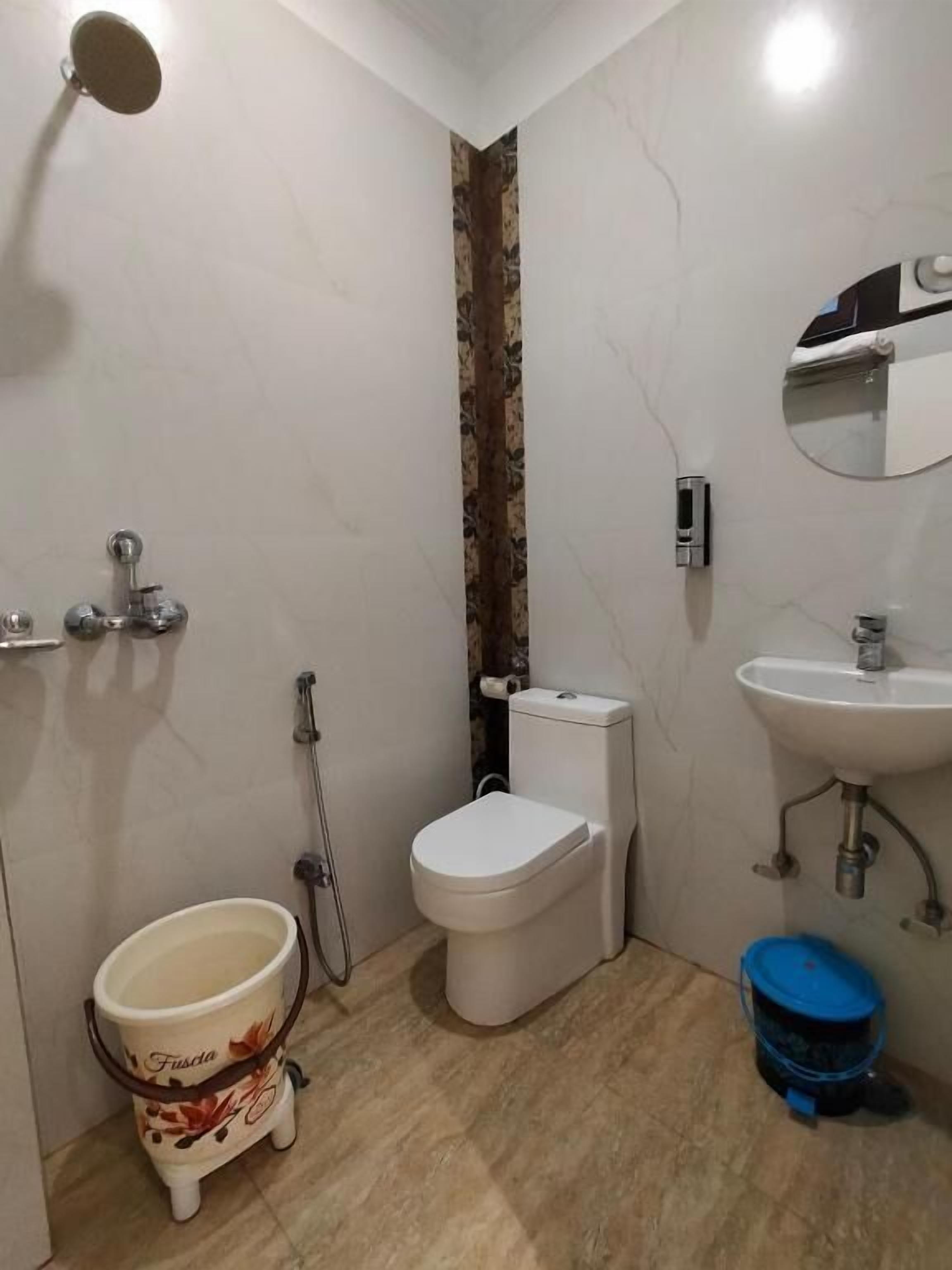 Een badkamer met toilet, bidet, wastafel en prullenbak.