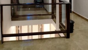Un intérieur spacieux agrémenté d’une rambarde en verre, d’une grande fenêtre avec du verre teinté en bleu et d’un escalier menant à un niveau supérieur.