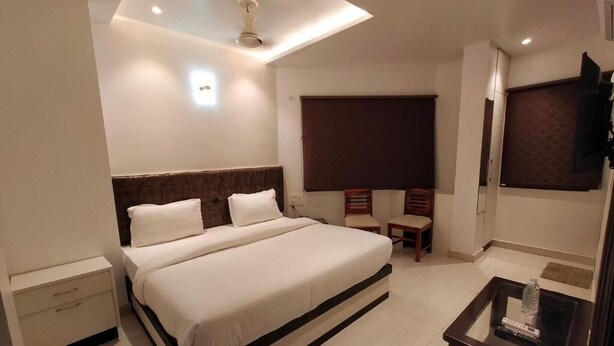 Une chambre d’hôtel moderne équipée d’un grand lit, d’un bureau avec une chaise, d’une télévision et d’un ventilateur de plafond.