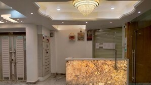 Un espace d’accueil avec un comptoir en marbre, un lustre et une porte fermée.