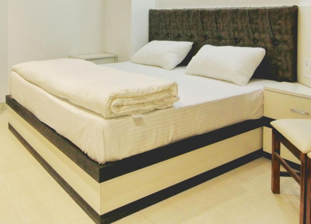 A bed with a dark headboard, a bedside table, and a chair.
