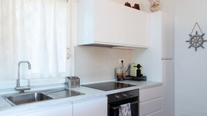 Una cocina moderna con armarios blancos, un lavamanos de acero inoxidable y un horno.