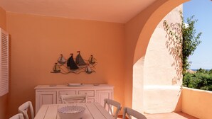 Un comedor con una mesa y sillas blancas, un armario blanco y una obra de arte colgada en la pared.