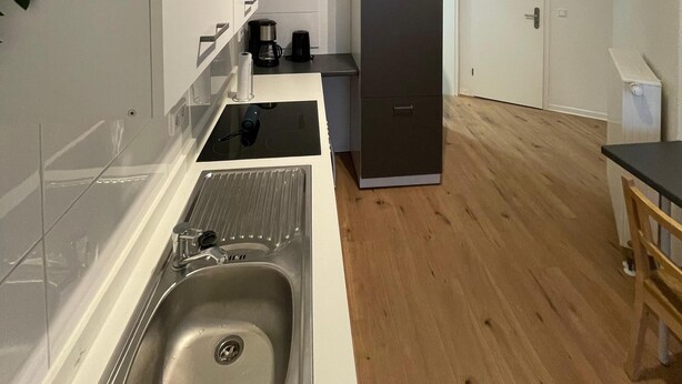 A compact kitchen with a sink, a coffee maker, and a refrigerator.