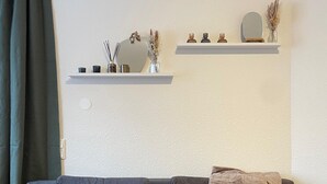 A modern living room with a grey sofa, a wooden coffee table, and two white shelves with decorative items.