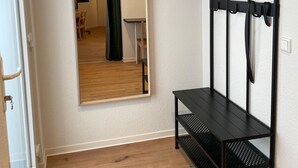 A narrow hallway with a wooden floor, a black metal bench, and a mirror on the wall.