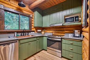 Une cuisine avec des meubles en bois, un four à micro-ondes, un four traditionnel et un évier.