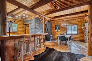 A log cabin interior with a bar area, dining space, and a fireplace. - Log Cabin Compound | 6BR/5.5BA | 2 Hot Tubs (Mount Hood Village)