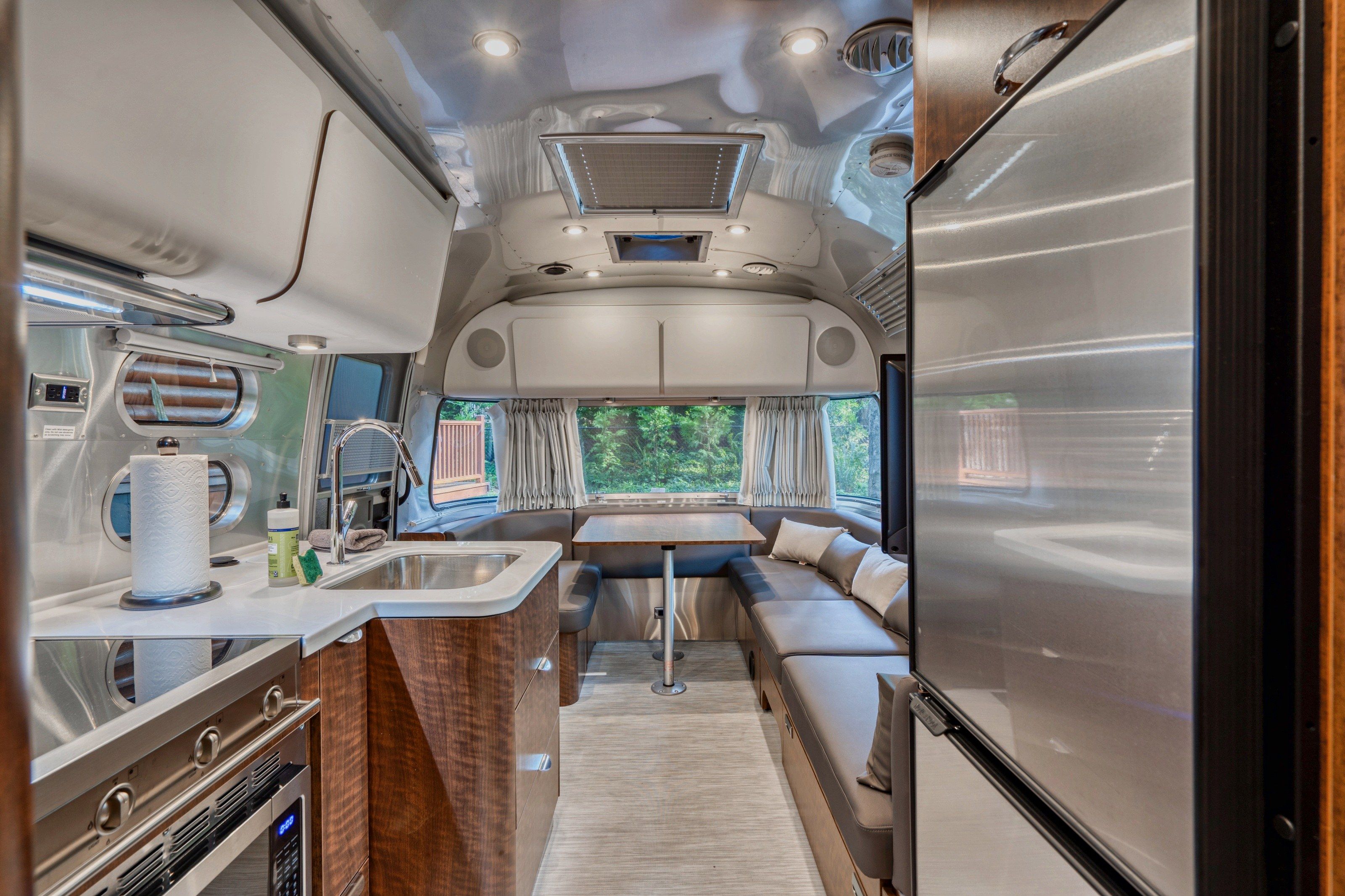 A compact RV interior with a kitchenette, a dining area, and a seating space.