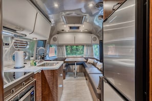 A compact RV interior with a kitchenette, a dining area, and a seating space. - Winter Log Cabin Compound • 2 Hot Tubs • Sleeps 14 (Mount Hood Village)