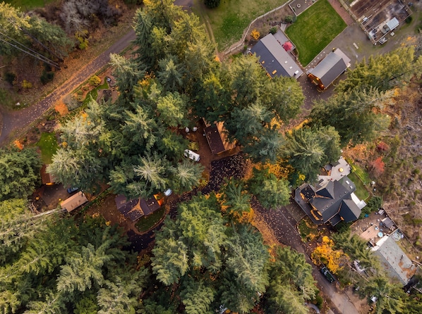 An aerial view of a residential area with multiple houses, roads, and a large green field. - Log Cabin Compound | 6BR/5.5BA | 2 Hot Tubs (Mount Hood Village)