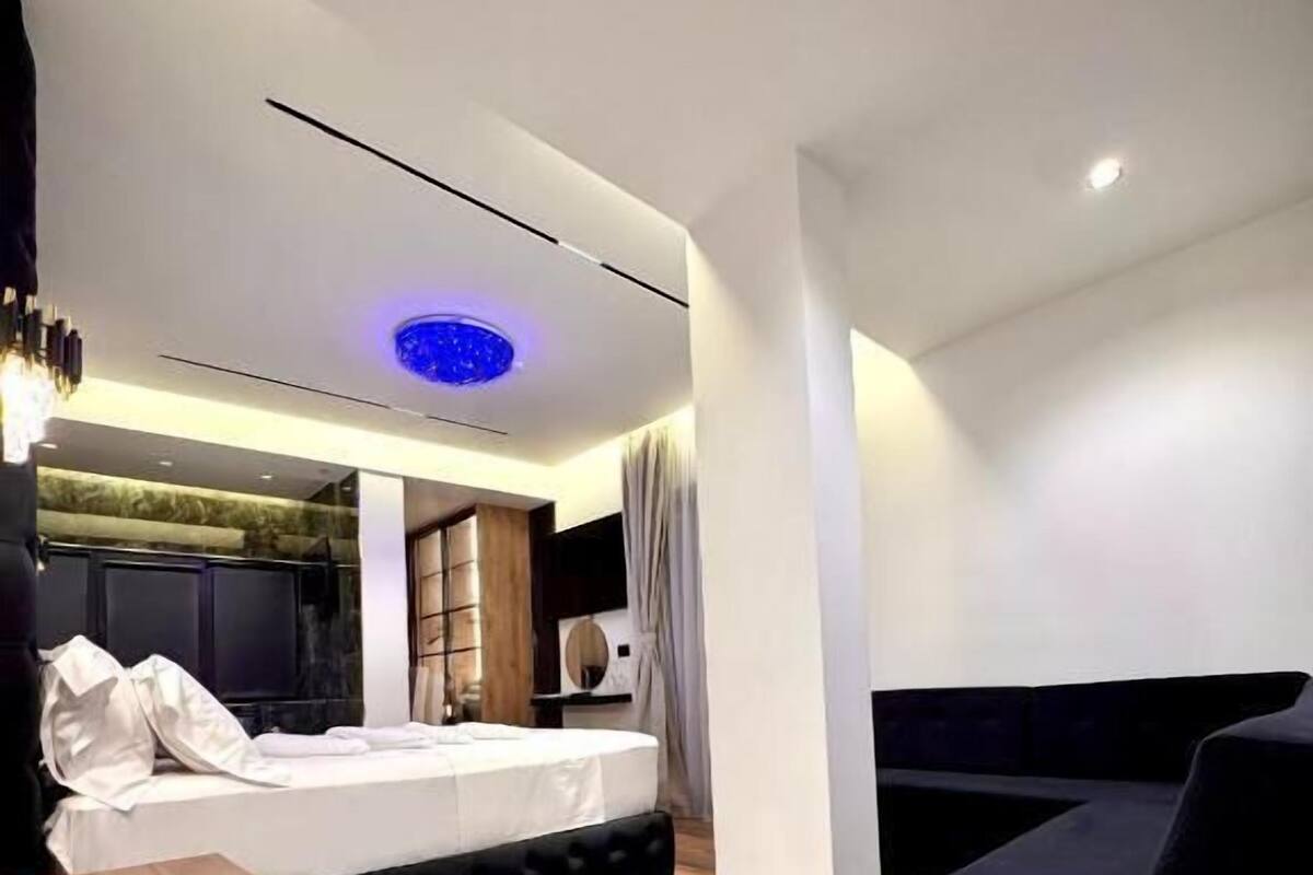 A modern bedroom with a bed, a sofa, and a large rug.