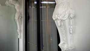 A white architectural detail with a sculpted figure, possibly a relief, on a wall. - Martin Empire (Gjirokastër)