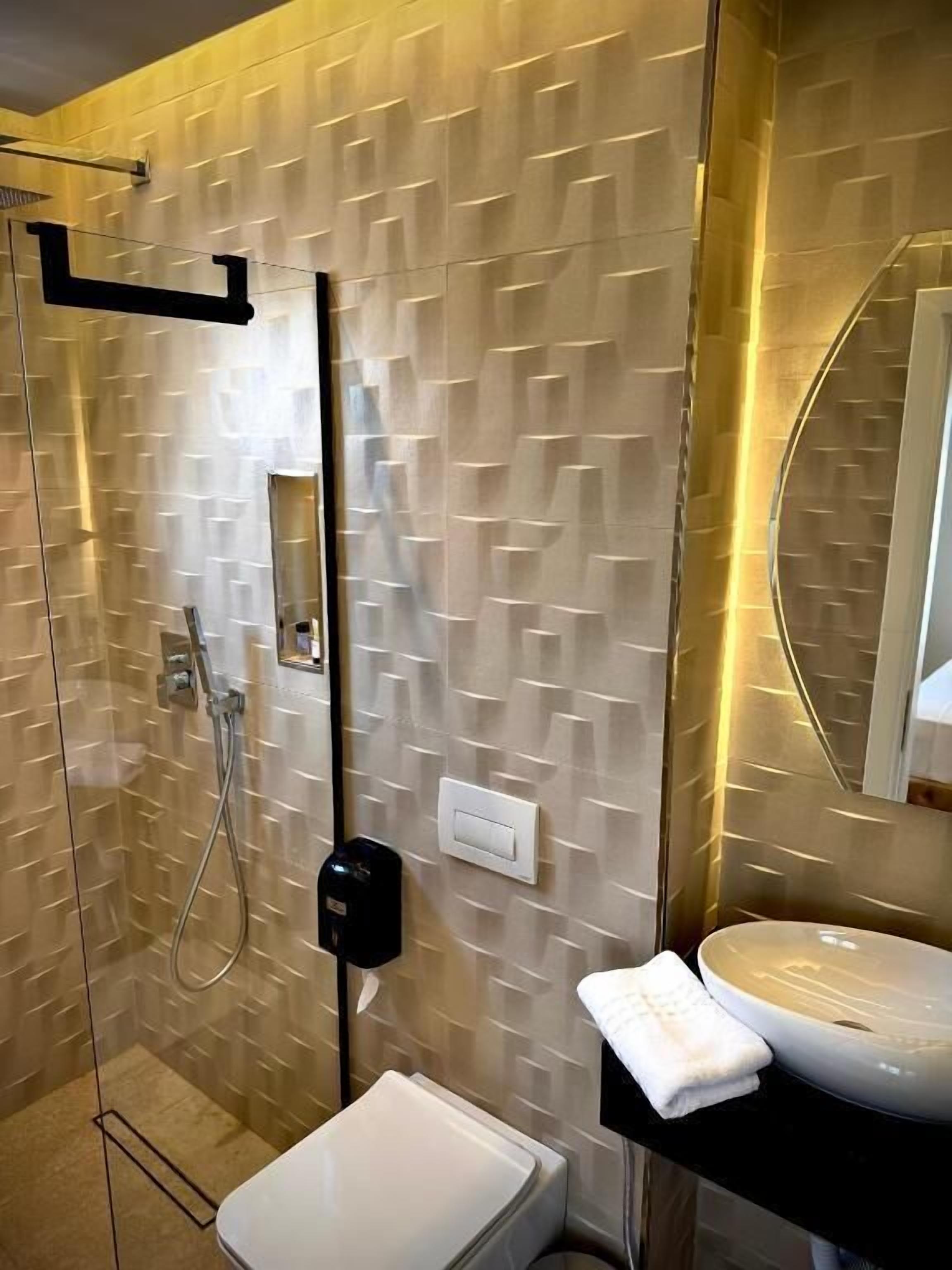 A modern bathroom with a glass shower enclosure, a white sink, and a large mirror.