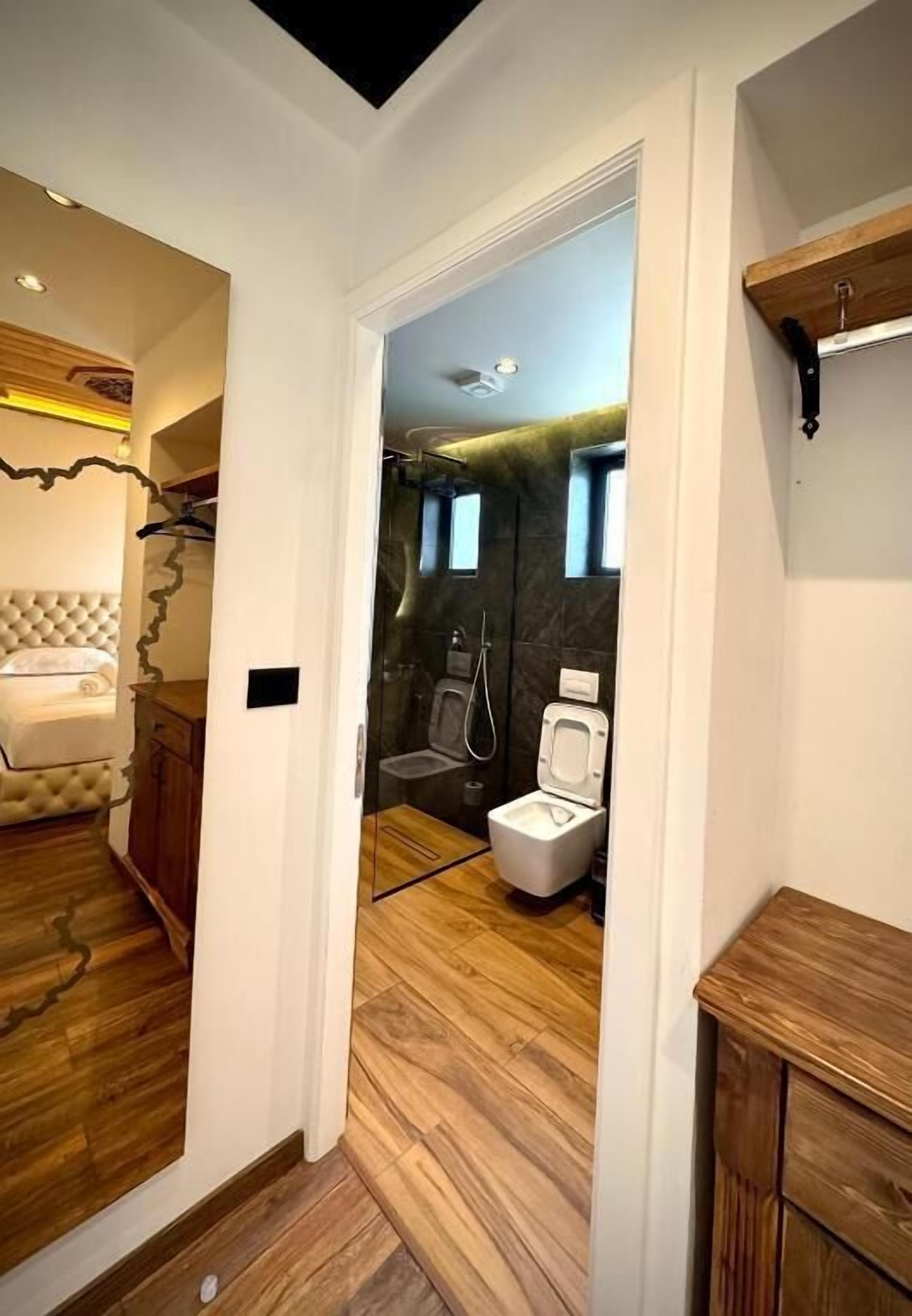 Un baño moderno con ducha envuelta en vidrio, inodoro blanco y tocador de madera.