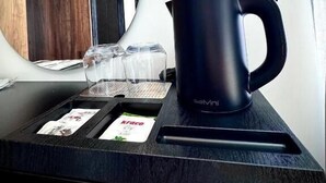 A kitchen counter with a black coffee maker, a glass container, and a card with a logo. - Martin Empire (Gjirokastër)