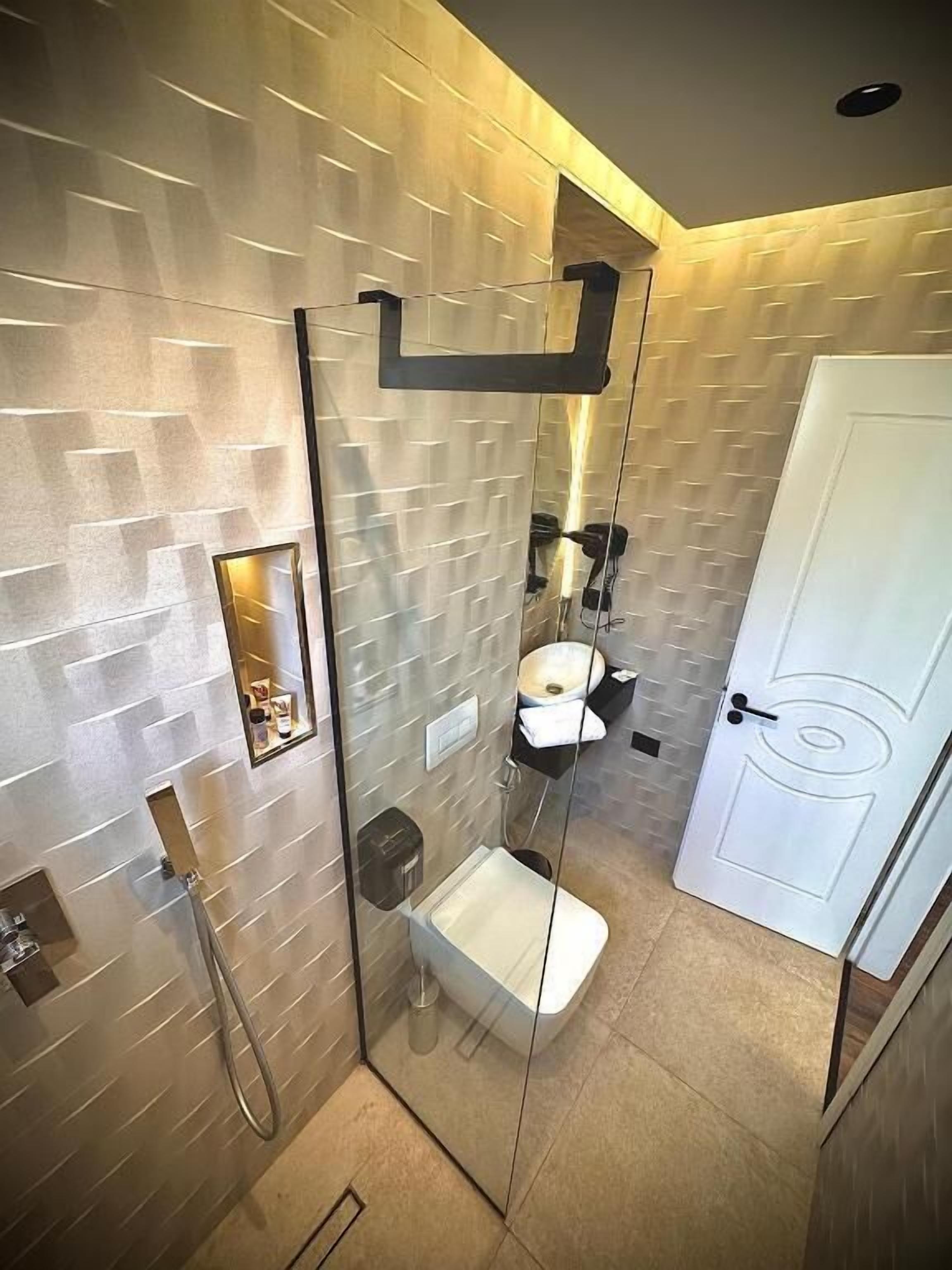 Un baño moderno con ducha de vidrio, inodoro blanco y lavamanos.