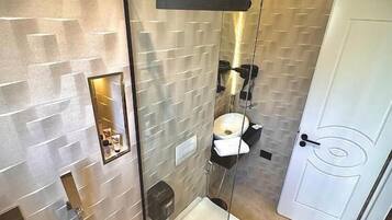 Un baño moderno con ducha de vidrio, inodoro blanco y lavamanos.
