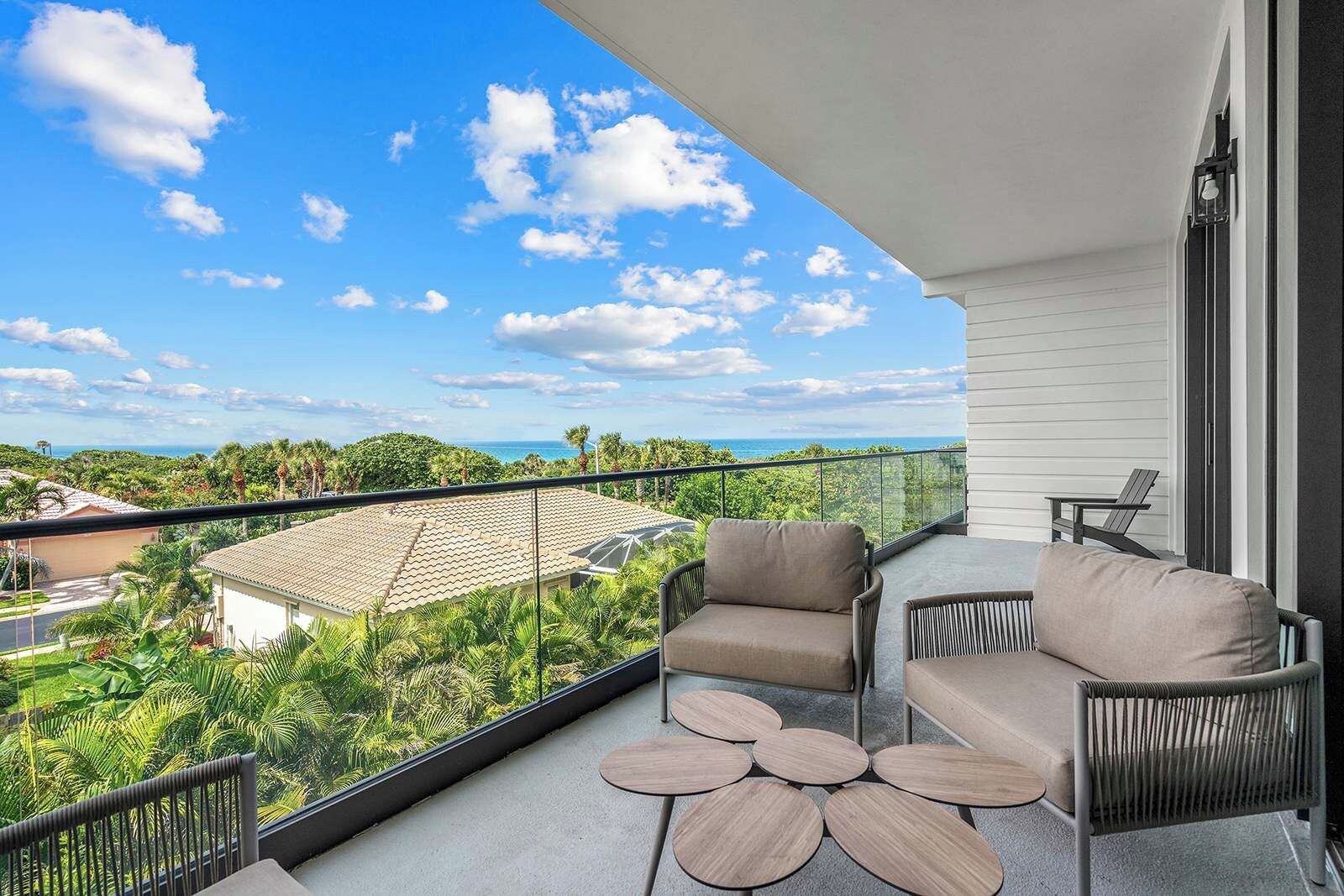 A balcony with a view of the ocean, two chairs, and a small table.