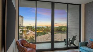 A modern living room with a large sliding glass door leading to a balcony with a city view.