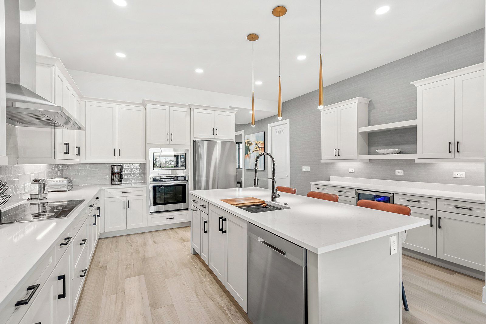 A modern kitchen with white cabinetry, stainless steel appliances, and pendant lighting.