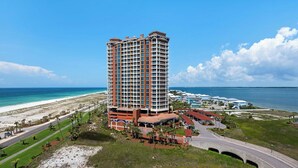 A high-rise hotel with a beach view, featuring multiple balconies and a central courtyard.