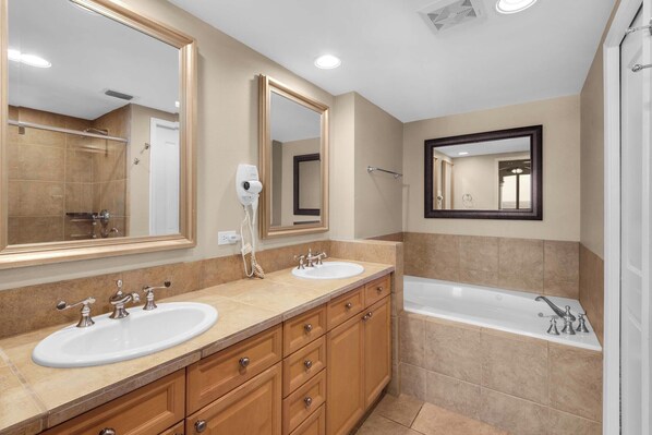 Un baño moderno con dos lavamanos, un espejo grande y una bañera.