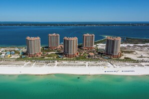 Un hotel de gran altura con vista a la playa, que cuenta con varios balcones y una zona de piscina.
