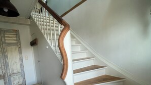 Eine Treppe mit Holzsitzstufen und weißen Geländern, die zu einer oberen Etage führt.