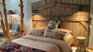 Ein Schlafzimmer mit einem hölzernen Kopfteil, floralem Bettbezug, einem Nachttisch und einer Lampe.