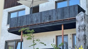 Ein modernes Gebäude mit Balkon, großen Fenstern und einem Holzzaun.