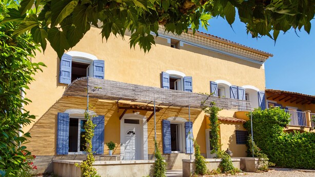 A two-story building with a yellow facade, blue shutters, and a gravel driveway. - La Ritournelle in Provence, 19 people, 4*. (Pernes-les-Fontaines)