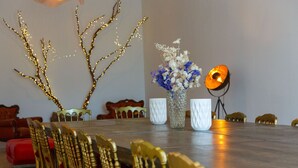 A dining table with golden chairs, a vase with flowers, and a decorative tree with lights. - La Ritournelle in Provence, 19 people, 4*. (Pernes-les-Fontaines)