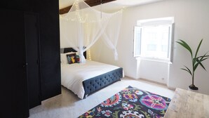 A bedroom with a bed, a canopy, a window, a plant, and a colorful rug. - La Ritournelle in Provence, 19 people, 4*. (Pernes-les-Fontaines)