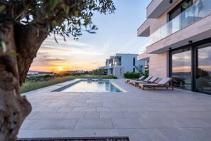 A modern outdoor pool area with lounge chairs and a view of the sunset. - Villa Belvedere 1 Zadarvillas (Sveti Filip i Jakov)