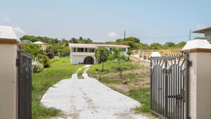 Un chemin bordé de portails mène à une maison dotée d’une entrée couverte et d’une petite arche.