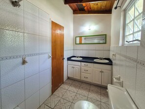 Ein kleines Badezimmer mit zwei Waschbecken, einer Toilette und einer Holztür.
