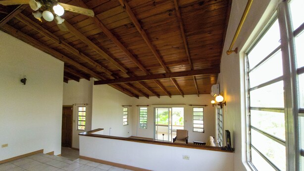 Une pièce spacieuse avec un plafond haut, de grandes fenêtres et une structure en poutres apparentes.