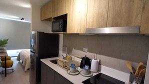 Una cocina moderna con armarios de madera, un refrigerador negro, un microondas, un fregadero con encimera negra y una estufa.