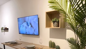 Un comedor moderno con una mesa de madera, taburetes amarillos, un televisor y una planta en maceta.