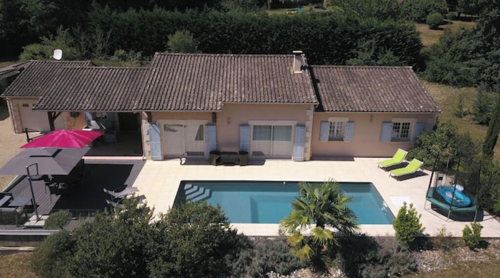 A two-story house with a swimming pool, outdoor seating, and a covered patio area.