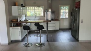 Una cocina moderna con armarios blancos, una isla central y un refrigerador de acero inoxidable.