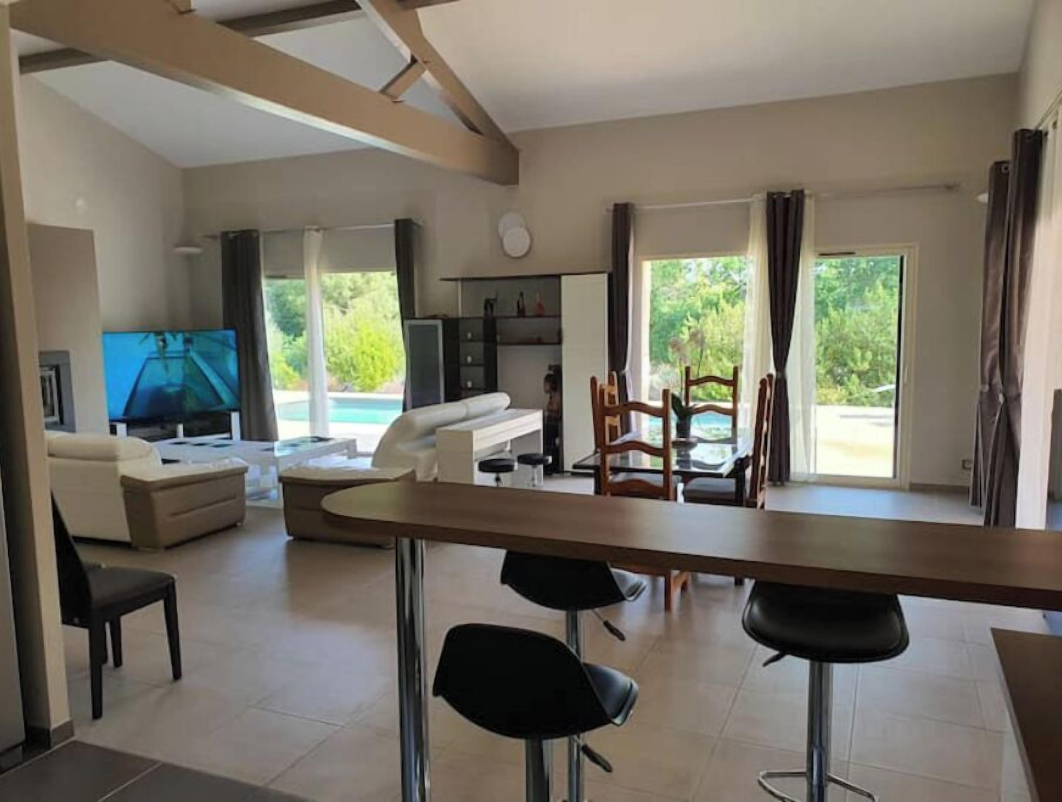 Un grand salon comprenant un téléviseur, un canapé et une table à manger avec des chaises.