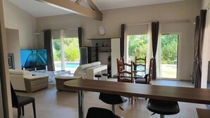 Amplia sala de estar con televisor, sofá y mesa de comedor con sillas.