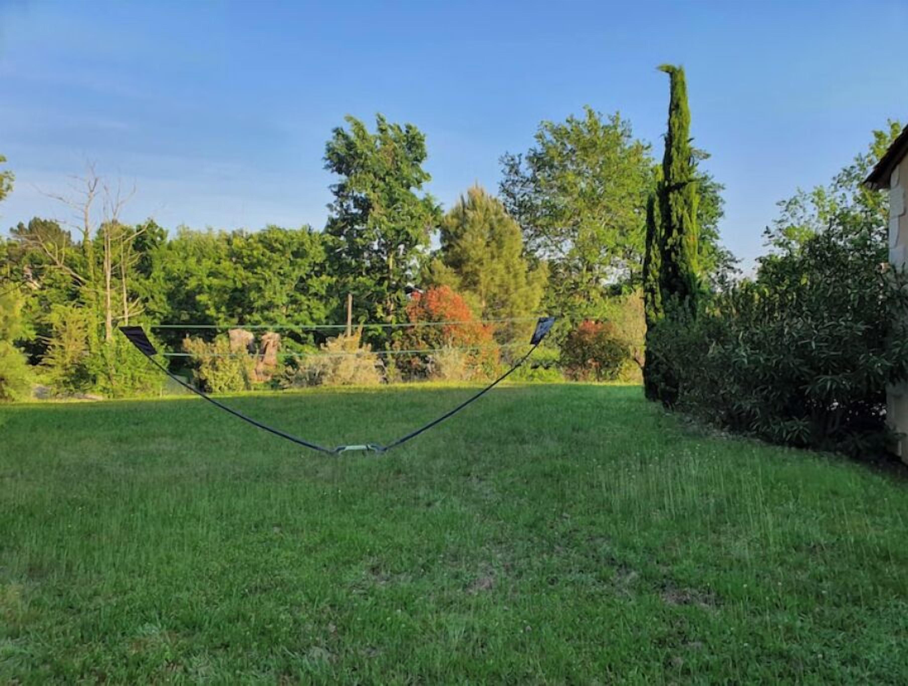 A grassy area with a metal structure, trees, and a building in the background.